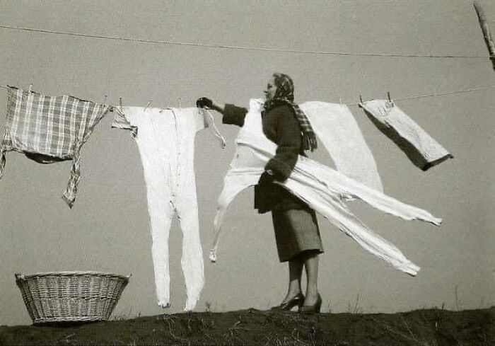 Un ama de casa sacando la ropa interior congelada del tendedero, años 40