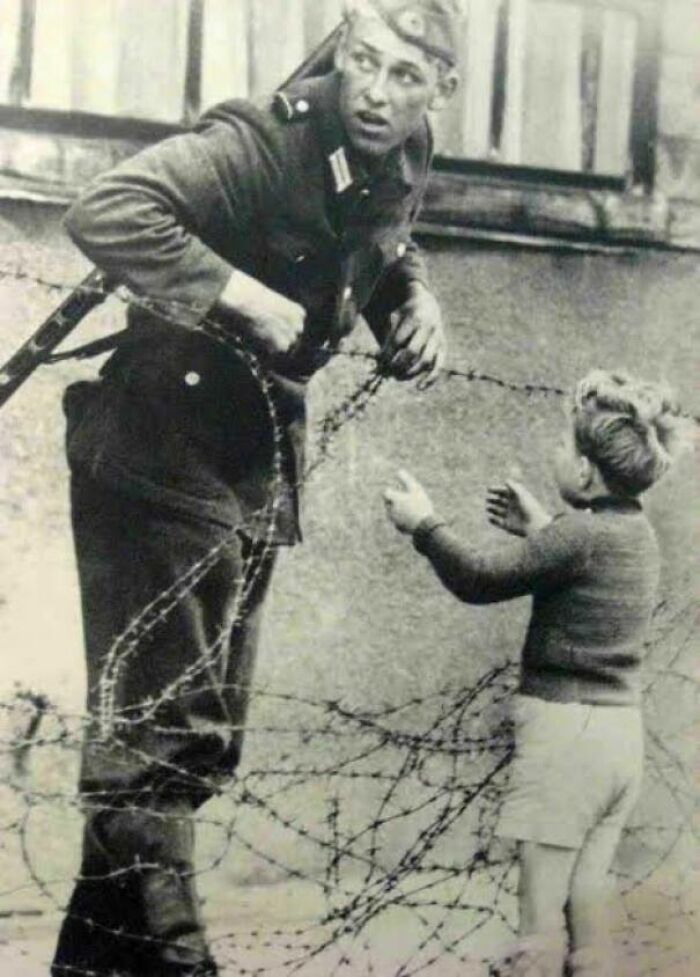 Soldado alemán ayuda a un niño a cruzar el Muro de Berlín, 1961