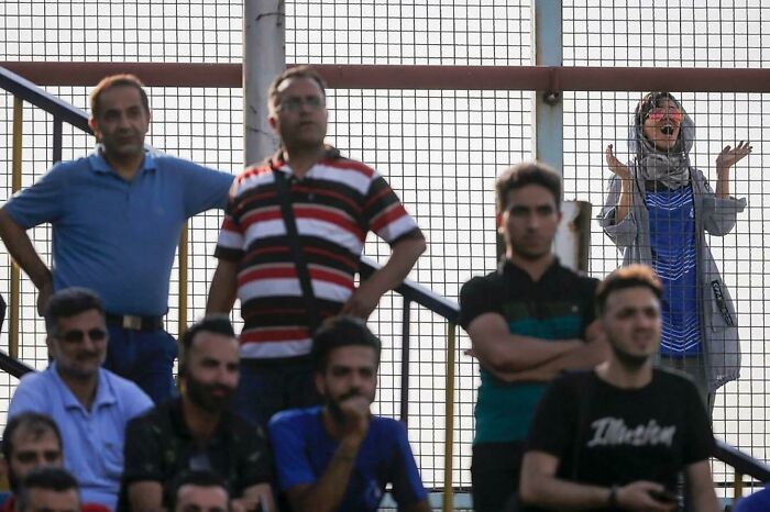 Una niña iraní anima a su equipo de fútbol favorito desde detrás de la valla, ya que a las mujeres iraníes no se les permite entrar en los estadios