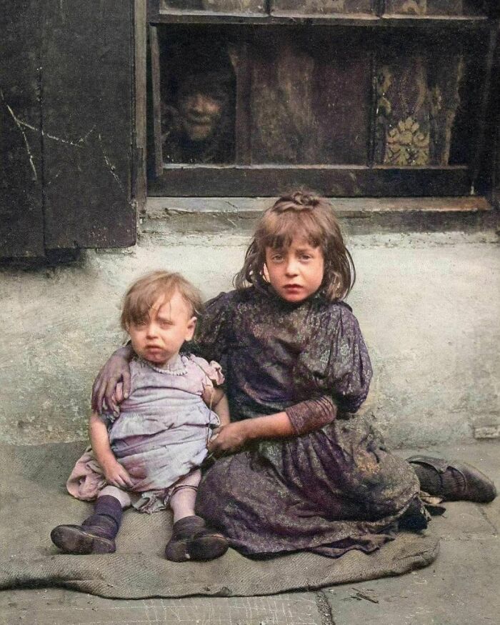 Victorian Poverty, 1900s. Annie, Seven, And One-Year-Old Nellie, Sit Sad And Hungry On Sacking Outside Their House In Spitalfields. They Were Among Ten Children Born To Single Mother Annie Daniels. Five Of Their Siblings Died In Childhood.
