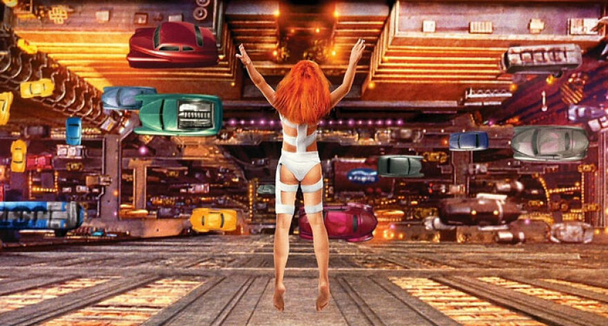 A woman with ginger hair flies from a building to a city road with many cars riding