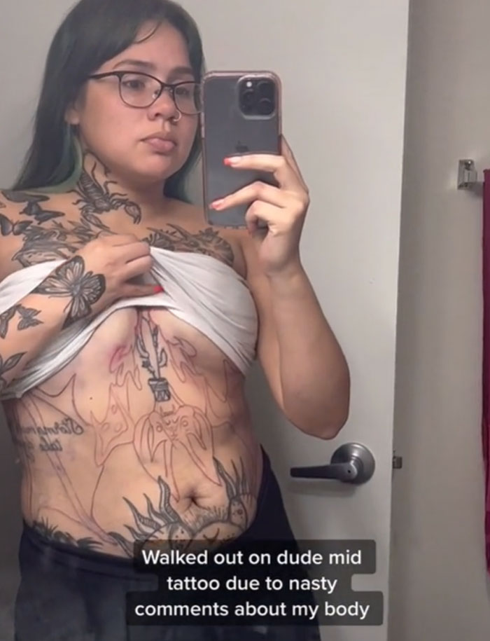 Woman showing unfinished tattoo in mirror after leaving session due to tattoo artist's behavior. Woman showing unfinished tattoo in mirror after leaving session due to tattoo artist's behavior.