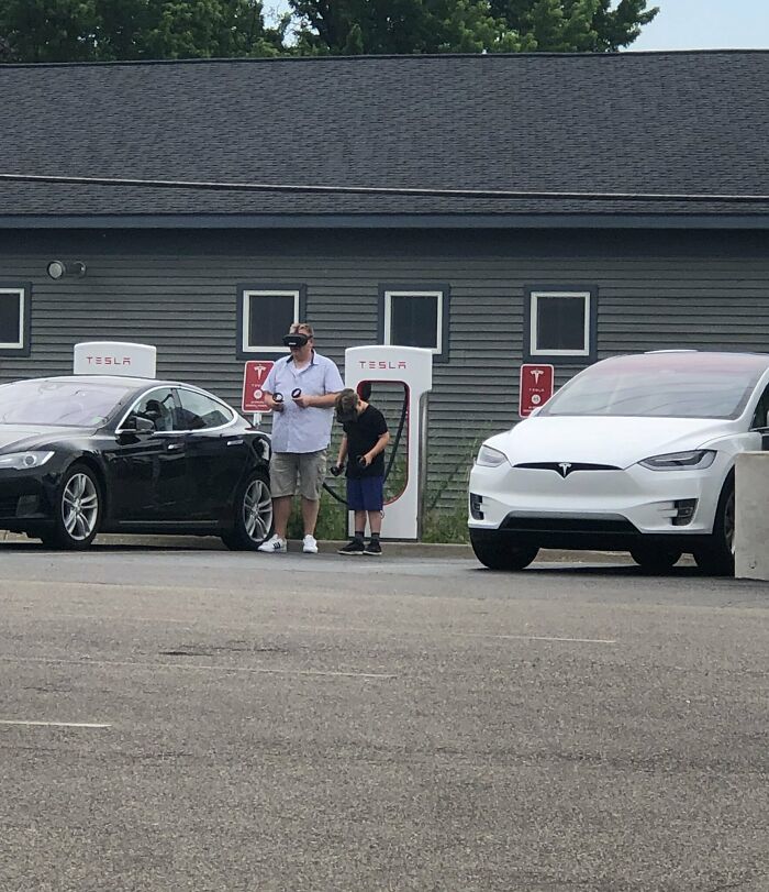 Just A Father And Son, Using VR Headsets, While Waiting For Their Tesla To Charge