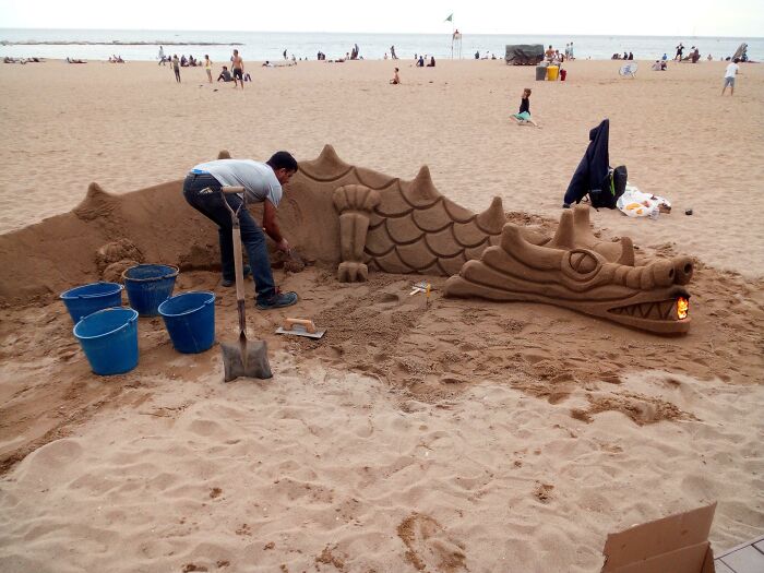 This Guy On A Beach In Barcelona Was Carving A Dragon Out Of Sand, And Put A Fire In Its Mouth To Look Like It's Breathing Fire
