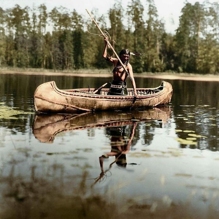 Un nativo americano, perteneciente al pueblo ojibwe, pescando con lanza en un lago de algún lugar de Minnesota, Estados Unidos. Fotografía tomada en 1908