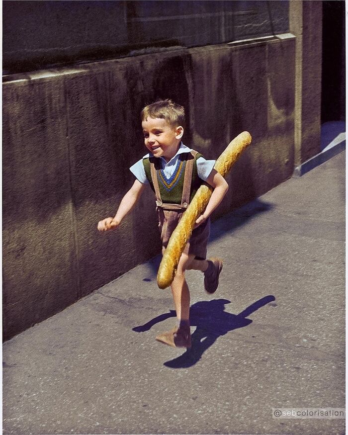 Un niño francés corriendo por una calle con una baguette fotografiado por el fotógrafo francés Willy Ronis en 1952
