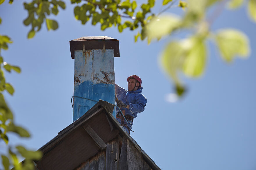 The Painter-Climber Paints The Chimney. A Worker On A Blue Sky Background.