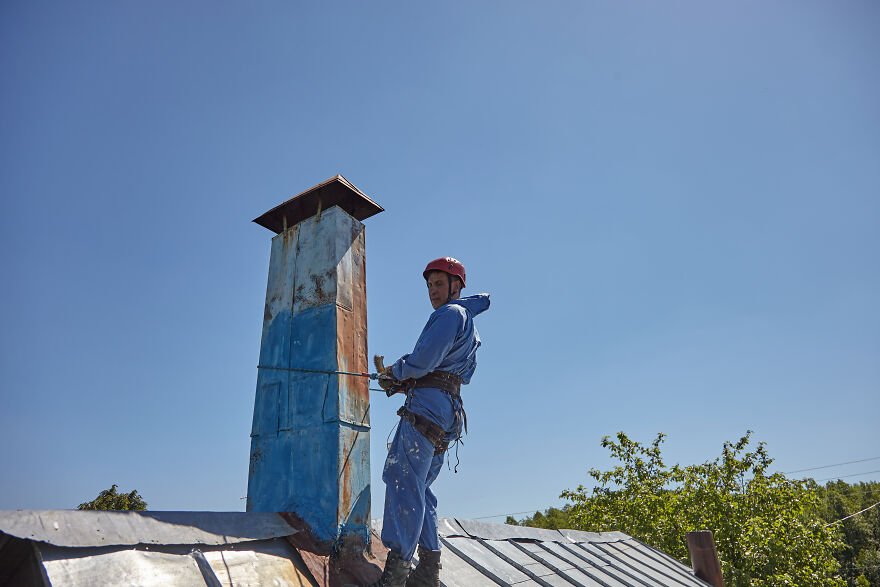 The Painter-Climber Paints The Chimney. A Worker On A Blue Sky Background.