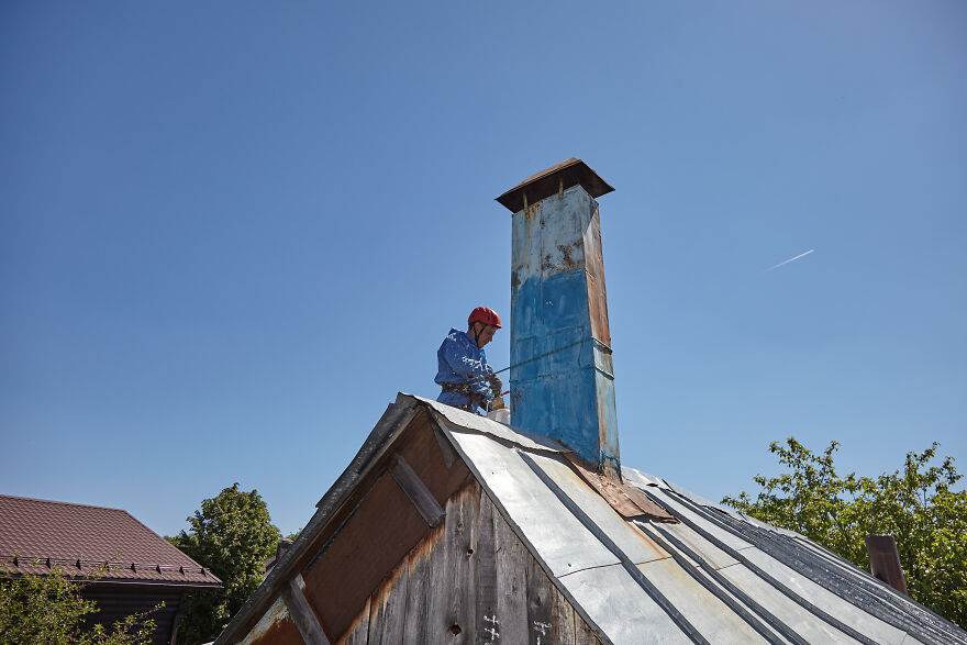 The Painter-Climber Paints The Chimney. A Worker On A Blue Sky Background.