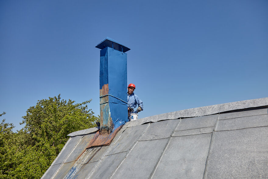 The Painter-Climber Paints The Chimney. A Worker On A Blue Sky Background.