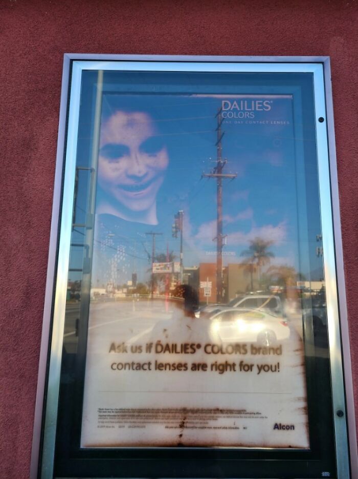 There's An Optometrist Business Near My House That Has This Giant Poster Outside Advertising Colored Contacts. It Seems To Have Aged In A "Wtf Is That A Demon?" Way