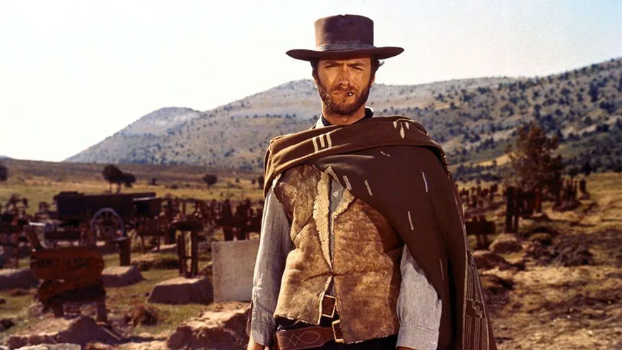 Stranger in the High Plains Drifter standing with a cigarette in his mouth and mountains in his background