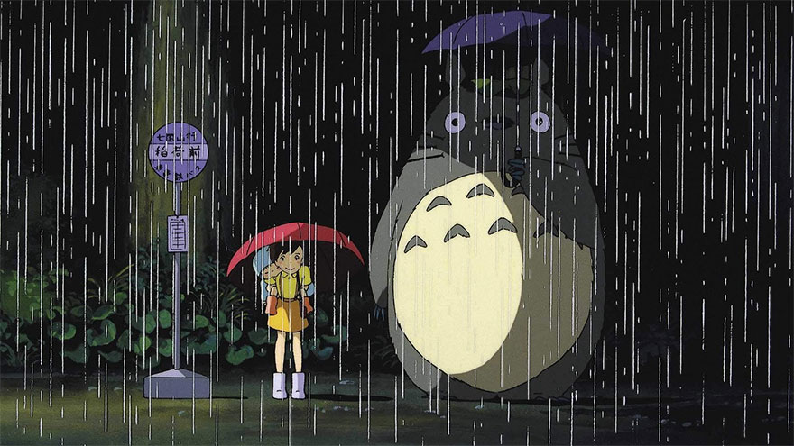 Totoro and Satsuki standing at the bus stop with umbrellas in the rain