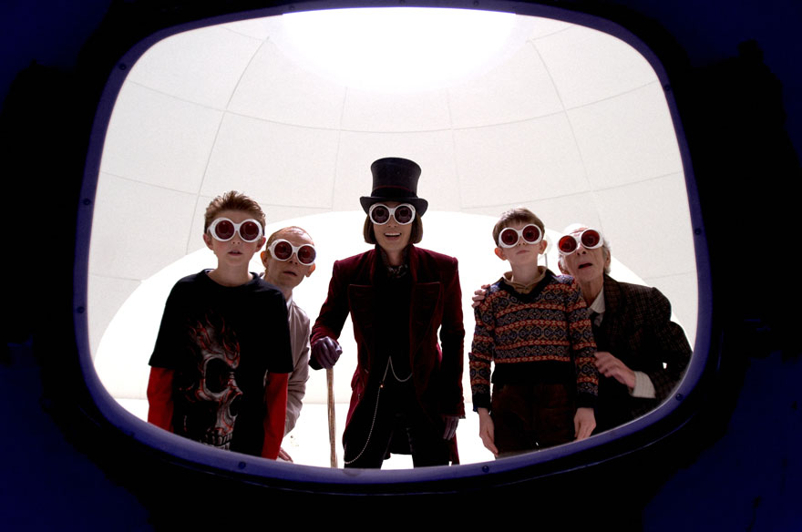Willy Wonka and four other characters wear funky sunglasses and are in a chocolate factory