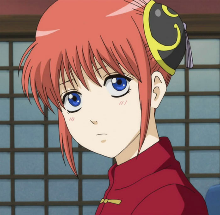 Anime girl with red hair and blue eyes, wearing a traditional red outfit, is gazing to the side in a room.