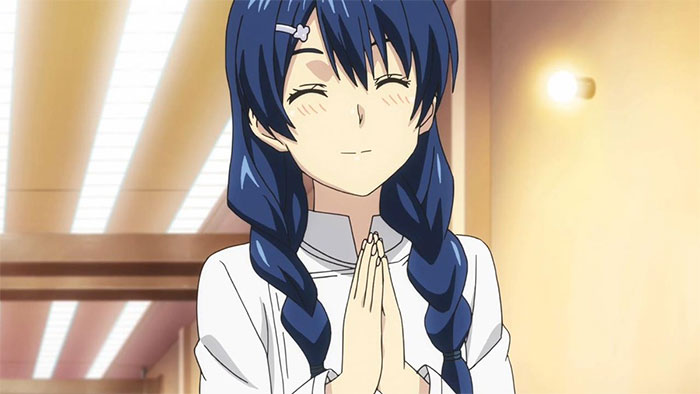 Smiling female anime character with braided blue hair, hands clasped, in a warmly lit room.