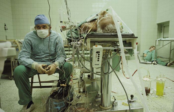 El Dr. Religa controla las constantes vitales de su paciente después de un transplante de corazón de 23 horas (con éxito). Su ayudante está durmiendo en la esquina, 1987