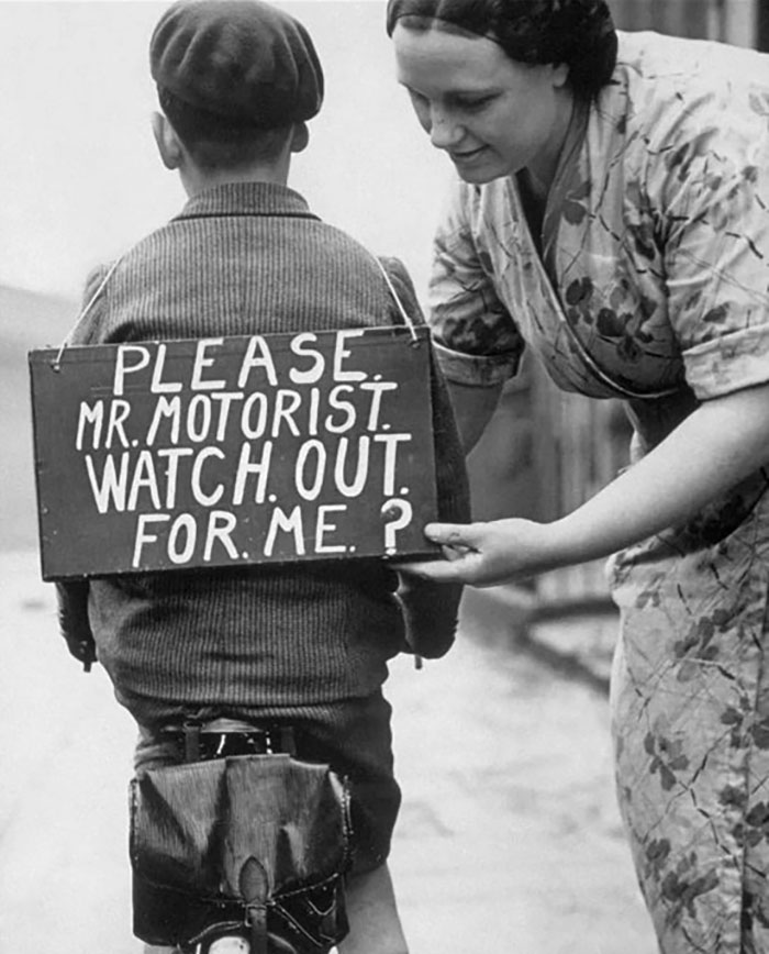 A Mother Places A Sign On Her Young Bicycle Rider's Back, 1937