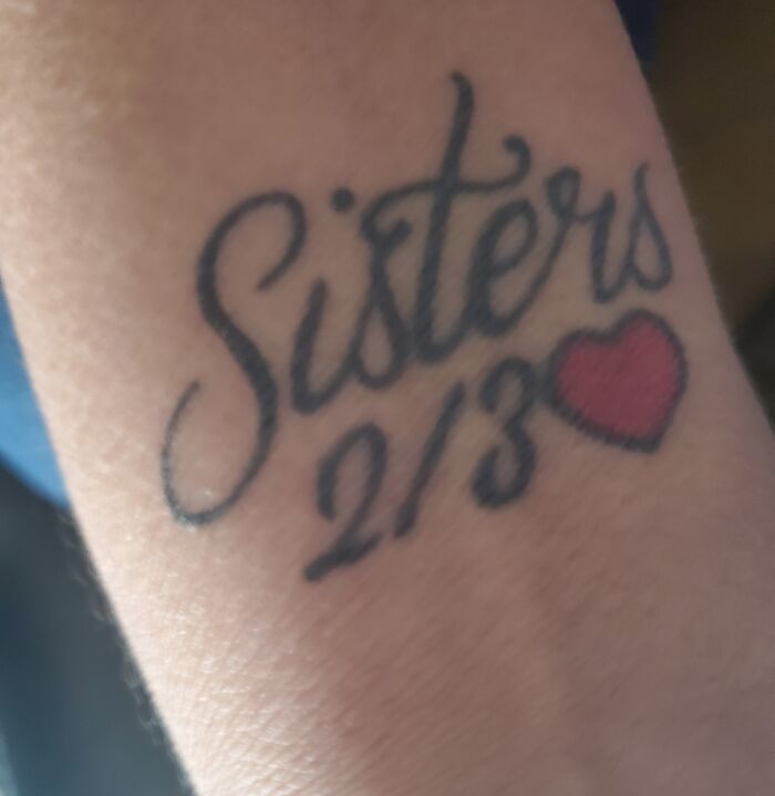 Tattoo of the word "Sisters" with a heart symbol, representing the bond between siblings.