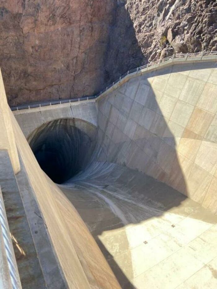 El túnel del vertedero de la presa Hoover, de 15 metros de ancho y 183 de profundidad. Se puede oír el agua corriendo en la oscuridad. La pasarela de arriba da una sensación de escala