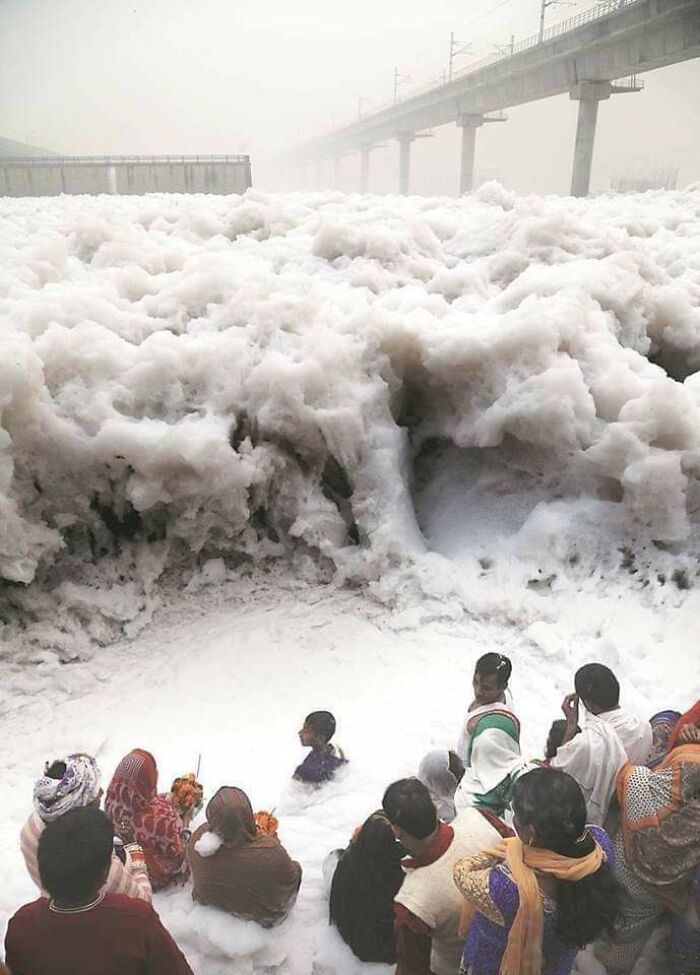 Gente ofreciendo oraciones en el río Yamuna, India, que está espumoso por los residuos industriales