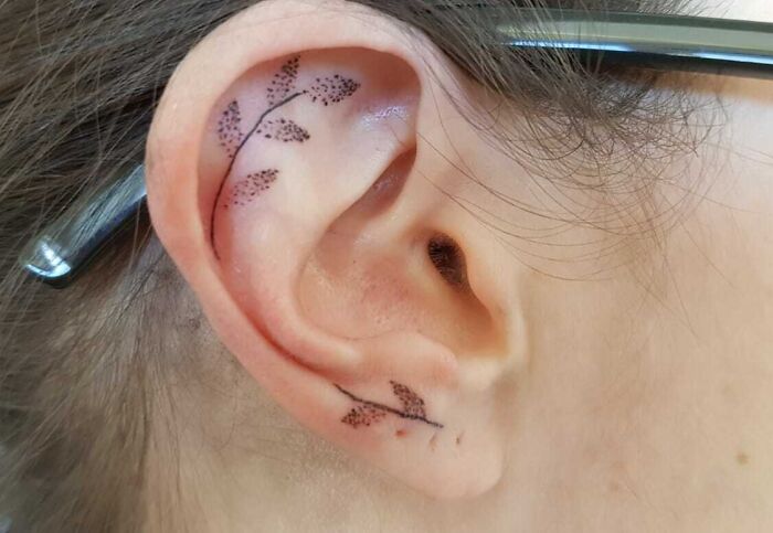 Ear with delicate leaf tattoo design, showcasing subtle ear tattoo art.