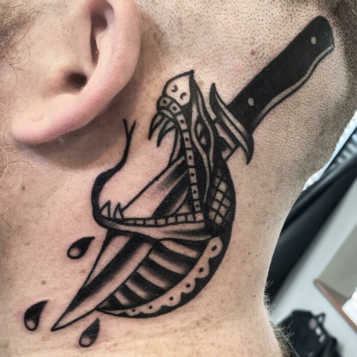 ear tattoo of a snake stabbed by a dagger