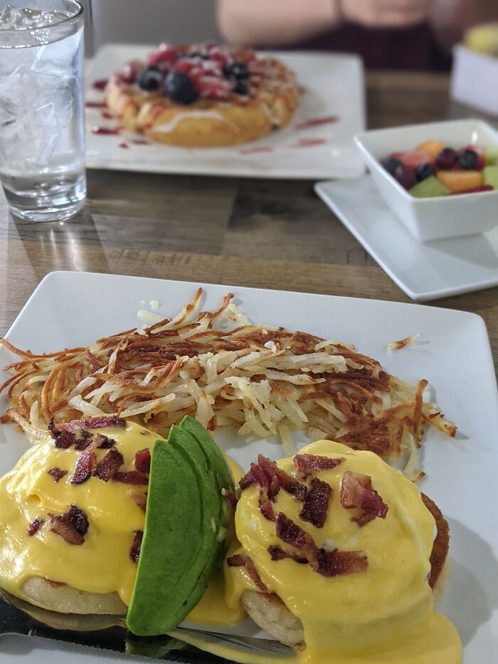 Eggs Benedict With Bacon, Avocado, And Hashbrows, While My Wife Chose To Get Berry Waffles In A Diner In Texas