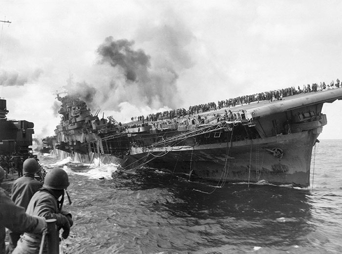 USS SANTA FE Lays Alongside USS FRANKLIN Rendering Assistance After The Carrier Had Been Hit And Set Afire By A Japanese Dive Bomber