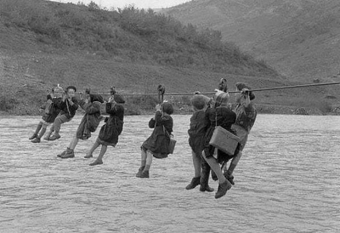 Niños que van a la escuela teniendo que cruzar un río en polea, Módena, Italia, 1959