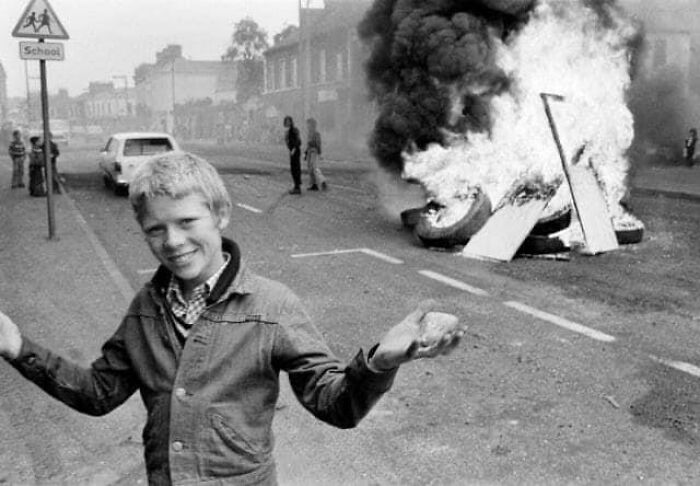 Northern Irish Boy Poses In Front Of Ira Car Bomb In Belfast, Northern Ireland, 1978