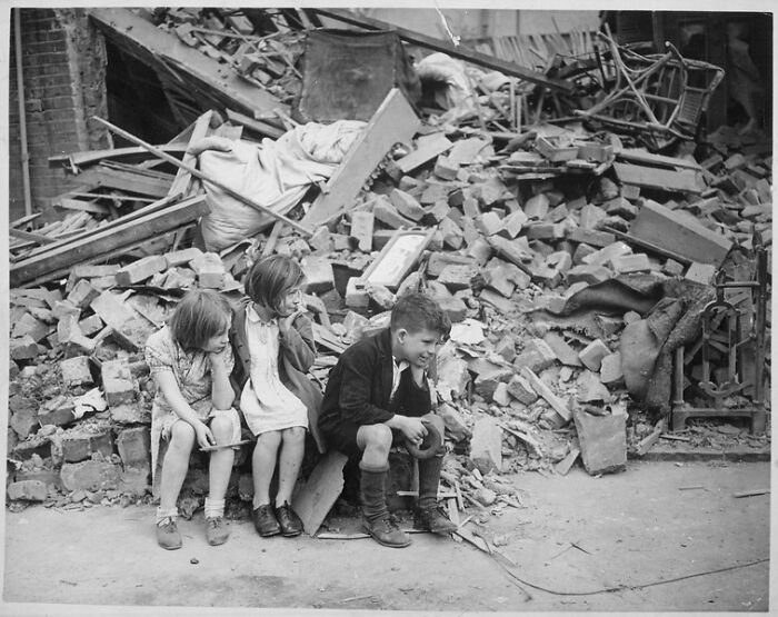 Children Of An Eastern Suburb Of London, Who Have Been Made Homeless By German Bombings, Sit Outside The Wreckage Of What Was Their Home, September 1940