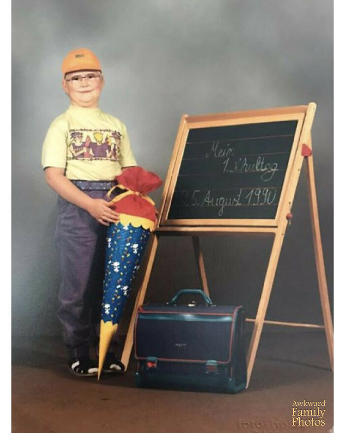 “My Husband’s 1st Day Of School Dressed In A Cap That Looks Like A Helmet, Old School Glasses And White Socks & Sandals While Holding His School-Issued ‘Schultuete’ "