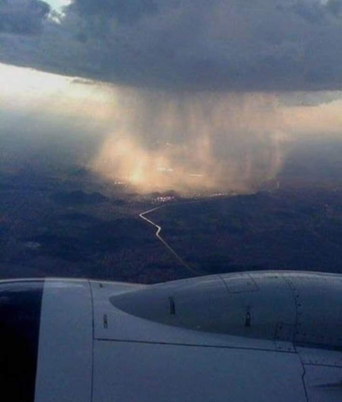 Escena de lluvia cayendo en el suelo tomada desde la ventanilla de un avión