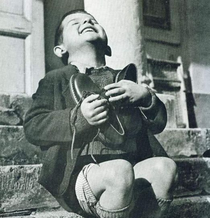 Un niño austriaco de 6 años brilla con una alegría ilimitada al coger un par de zapatos nuevos que le regaló la Cruz Roja Americana, al final de la Segunda Guerra Mundial, en 1945