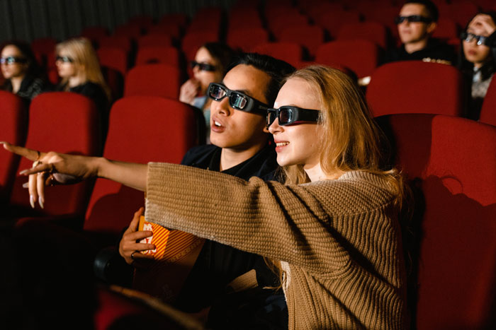Woman and man watching movie in the cinema and pointing