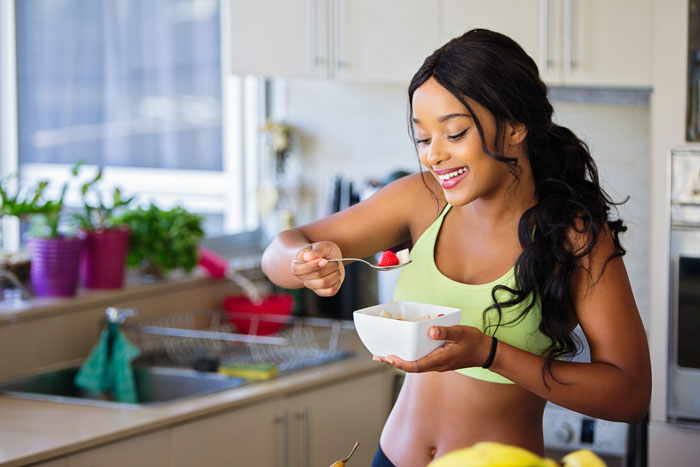 Woman wearing gym clothes eating cereal