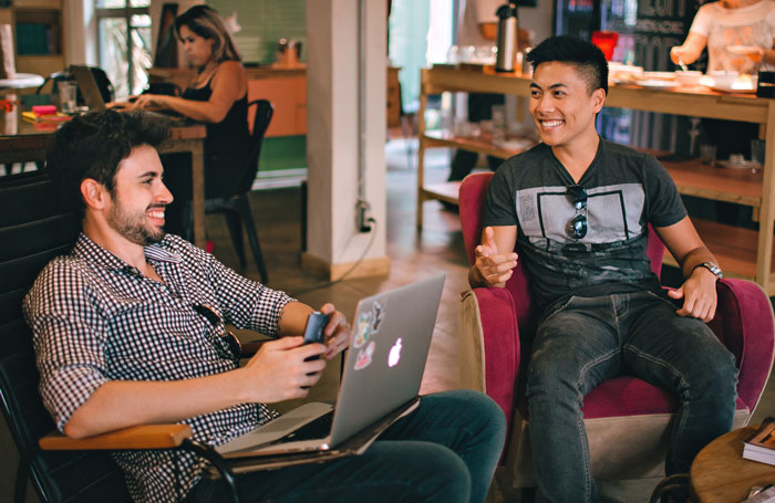 Friends sitting and talking while holding computer