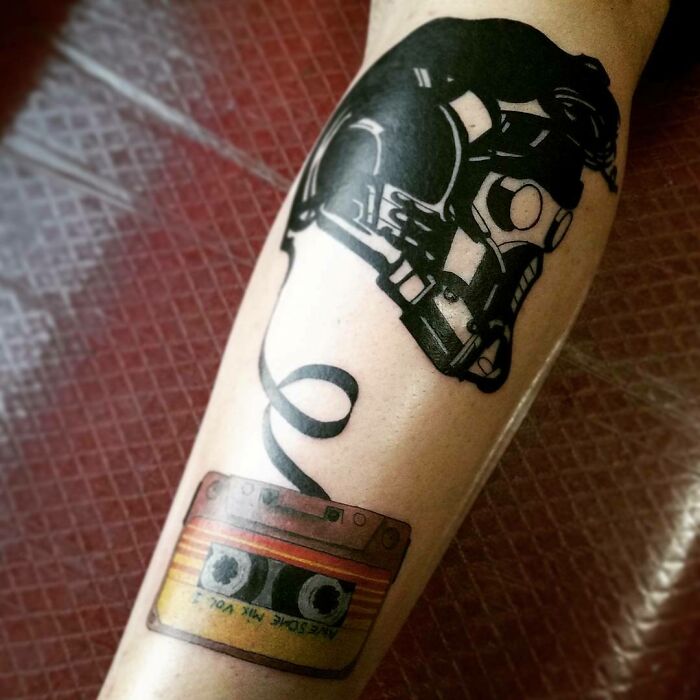 Marvel tattoo featuring a retro cassette tape and helmet design on a person's calf.