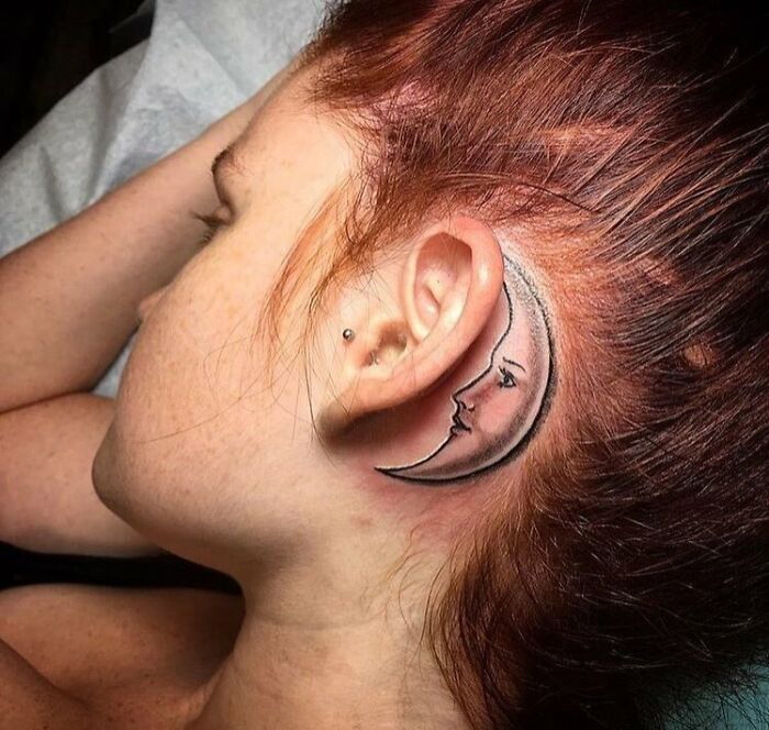 ear tattoo of a crescent moon with facial features 