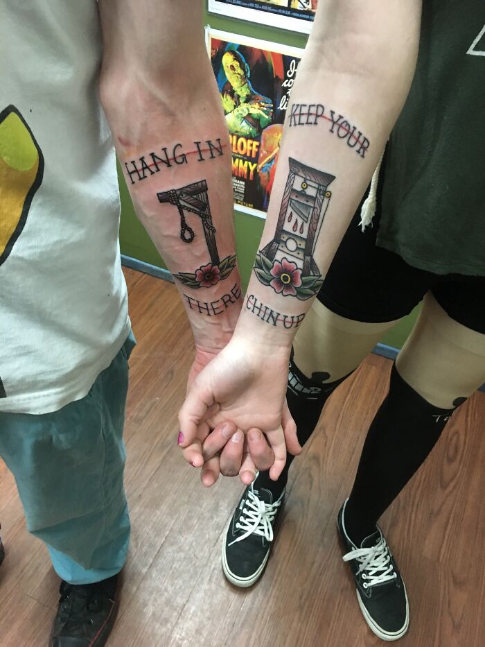 Two friends with matching best friend tattoos, featuring a noose and guillotine, symbolizing support and encouragement.