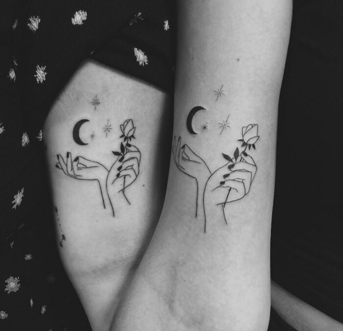 Matching best friend tattoos featuring hands holding roses under crescent moons and stars.