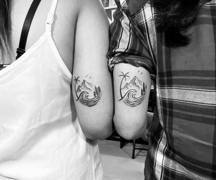 Matching best friend tattoos featuring mountains and waves on two people's arms.