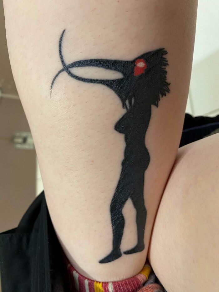Unique calf tattoo featuring a silhouette of a mythical creature with a red detail, showcasing artistic design.