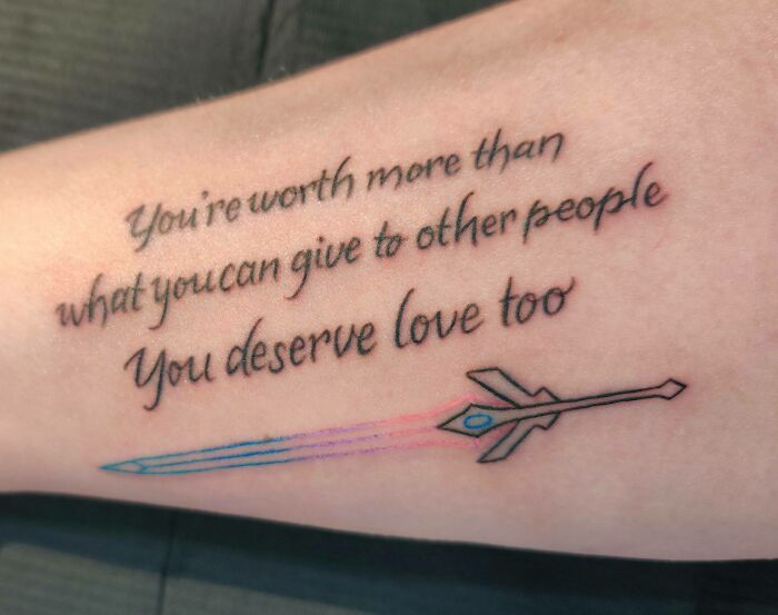 Inspirational word tattoo with text "You're worth more" and a colorful sword design.
