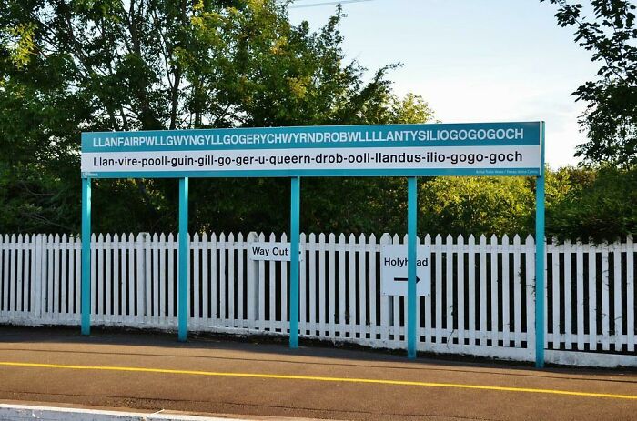 Train Station's Sign In The Welsh Town Of Llanfairpwllgwyngyllgogerychwyrndrobwllllantysiliogogogoch Has Phonetic Spelling To Assist Travelers With Pronunciation