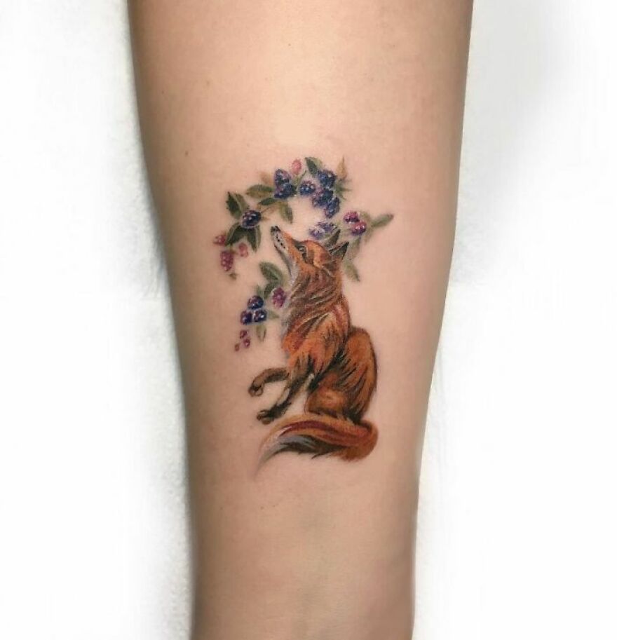 red fox in flowers tattoo on the forearm