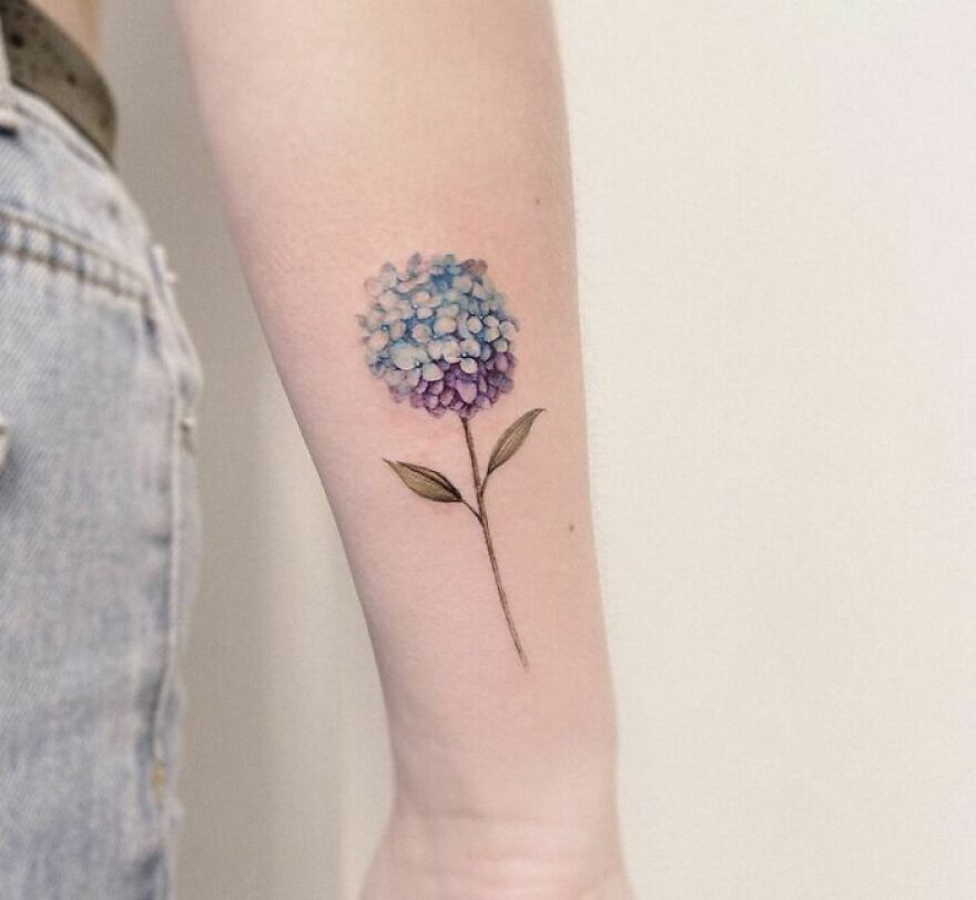 blue and purple flower tattoo on the forearm