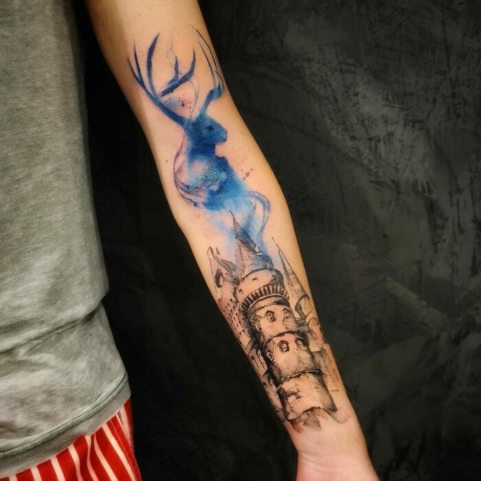 Arm with detailed Harry Potter tattoos featuring a blue stag and castle, ideal for fans of the Wizarding World.