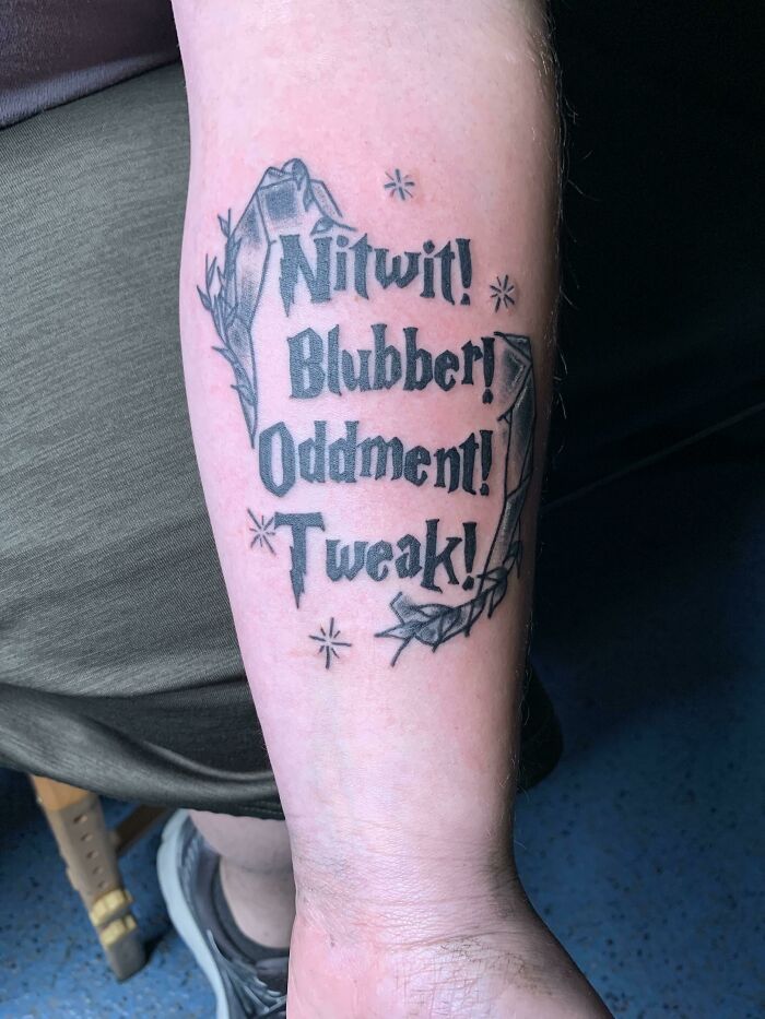 Harry Potter tattoo featuring Dumbledore's final words "Nitwit! Blubber! Oddment! Tweak!" on a person's forearm.